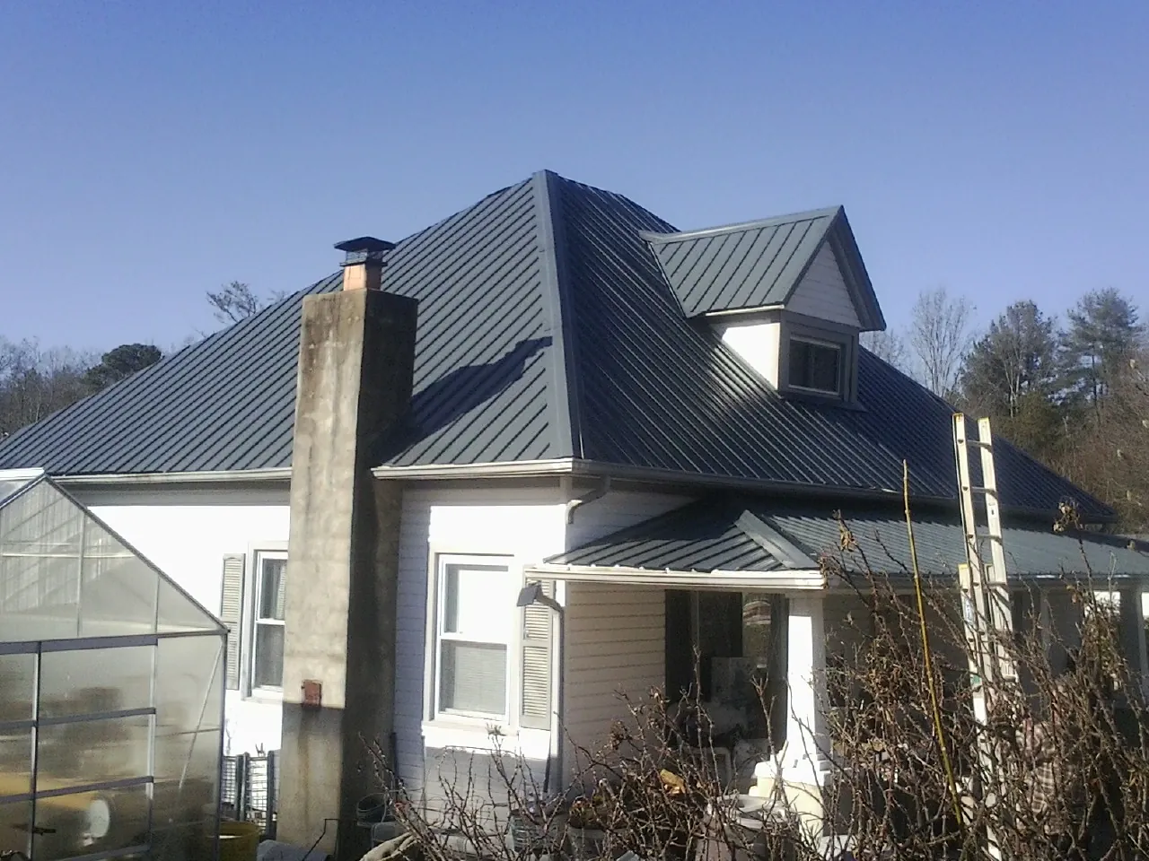 Dark blue standing seam metal roof on a white farmhouse with dormer — Slate & Tile Roof Repair by Roofing Brothers in Ojai
